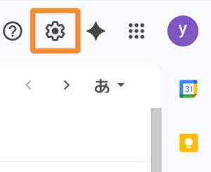 Gmail画面右上の設定アイコン(歯車マーク)がオレンジ枠で強調されている。